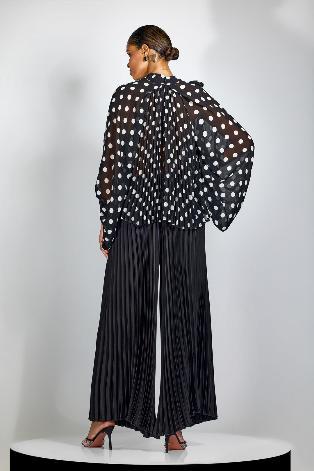 Styling-Beispiel: Alma Plisseehose mit weitem Bein und hohem Bund mit einem schwarzen Oberteil
