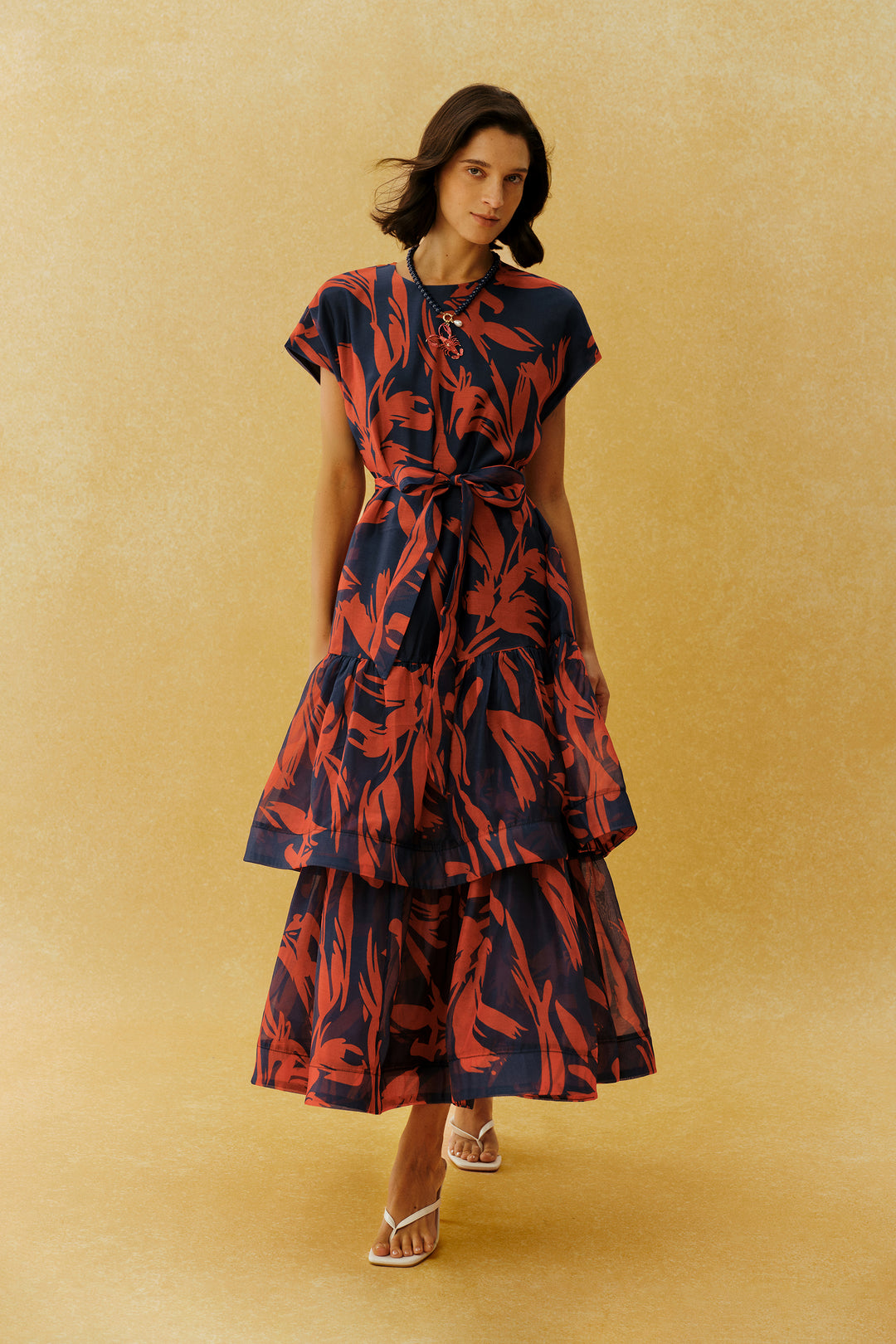 Model trägt das rote Maxikleid mit Blattprint und Bindegürtel - KYMA